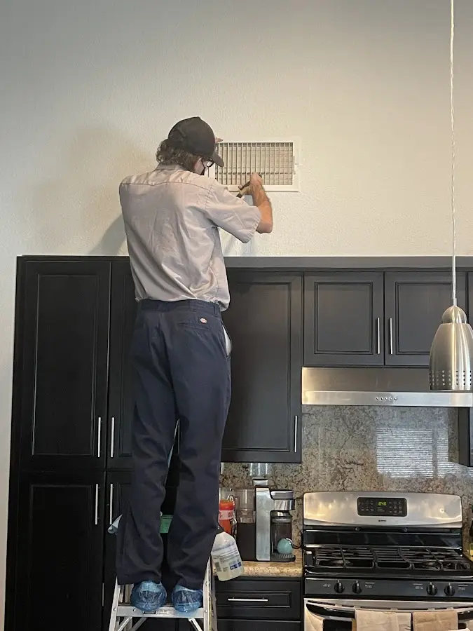 Technician inspecting an air vent during HVAC service in Monson
